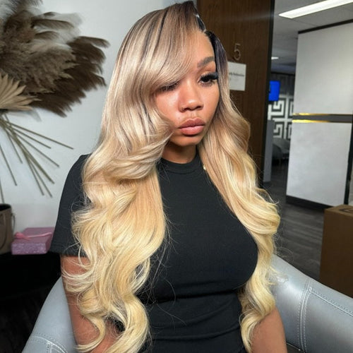 A woman sitting in a salon chair wearing a blonde custom wig that reaches up to her shoulders.